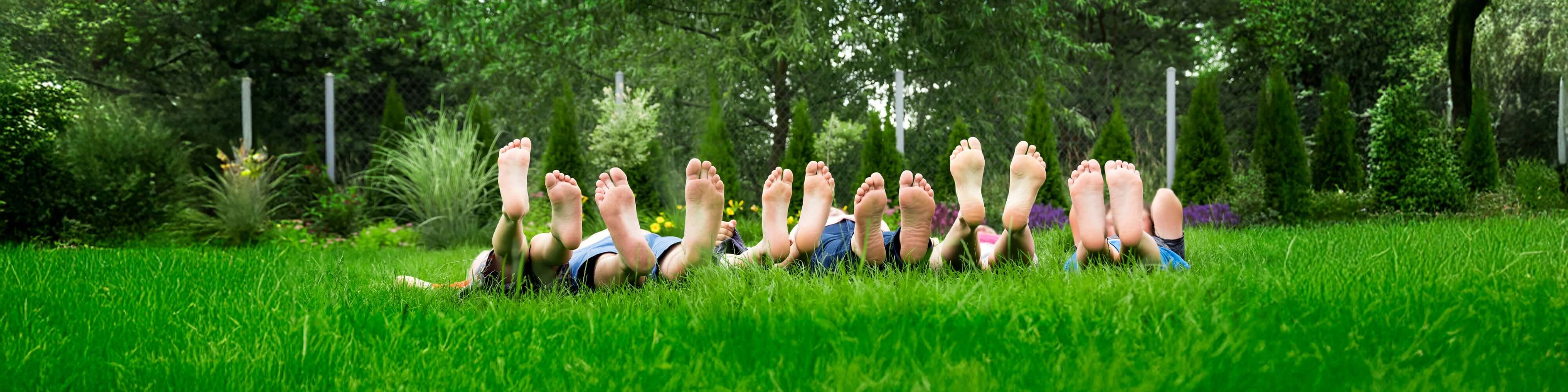 Kids supportive footwear displayed with children lying on grass, showcasing happy feet and comfortable footwear.