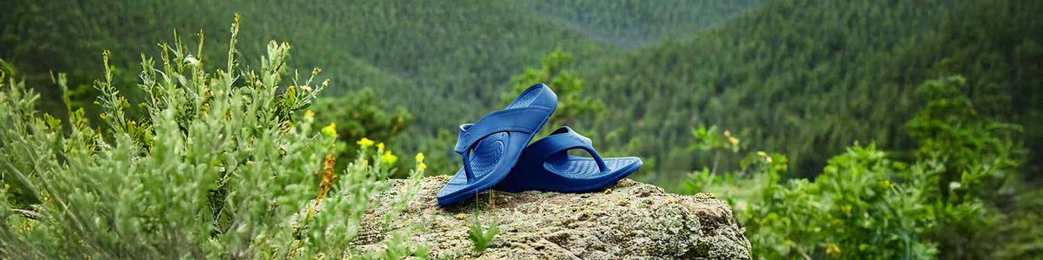 NuuSol sandals clearance sale resting on a rock with a scenic forest background.